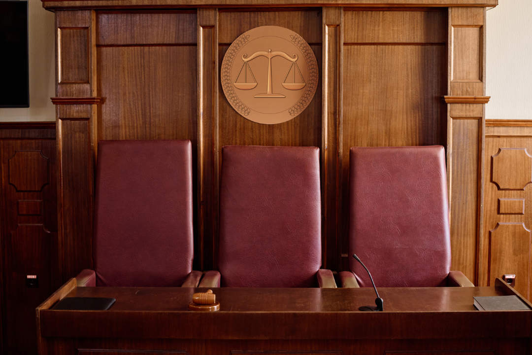 Wooden table with gavel, microphone and black leather folder with documents